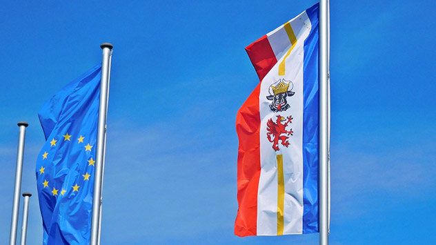 Die Flaggen der EU und von Mecklenburg-Vorpommern wehen im Wind.