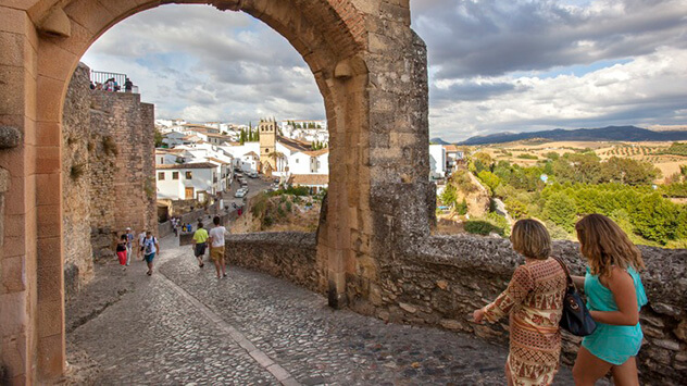 Besucher spazieren auf einer Stadtmauer eines Dorfes im andalusischen Hinterland.
